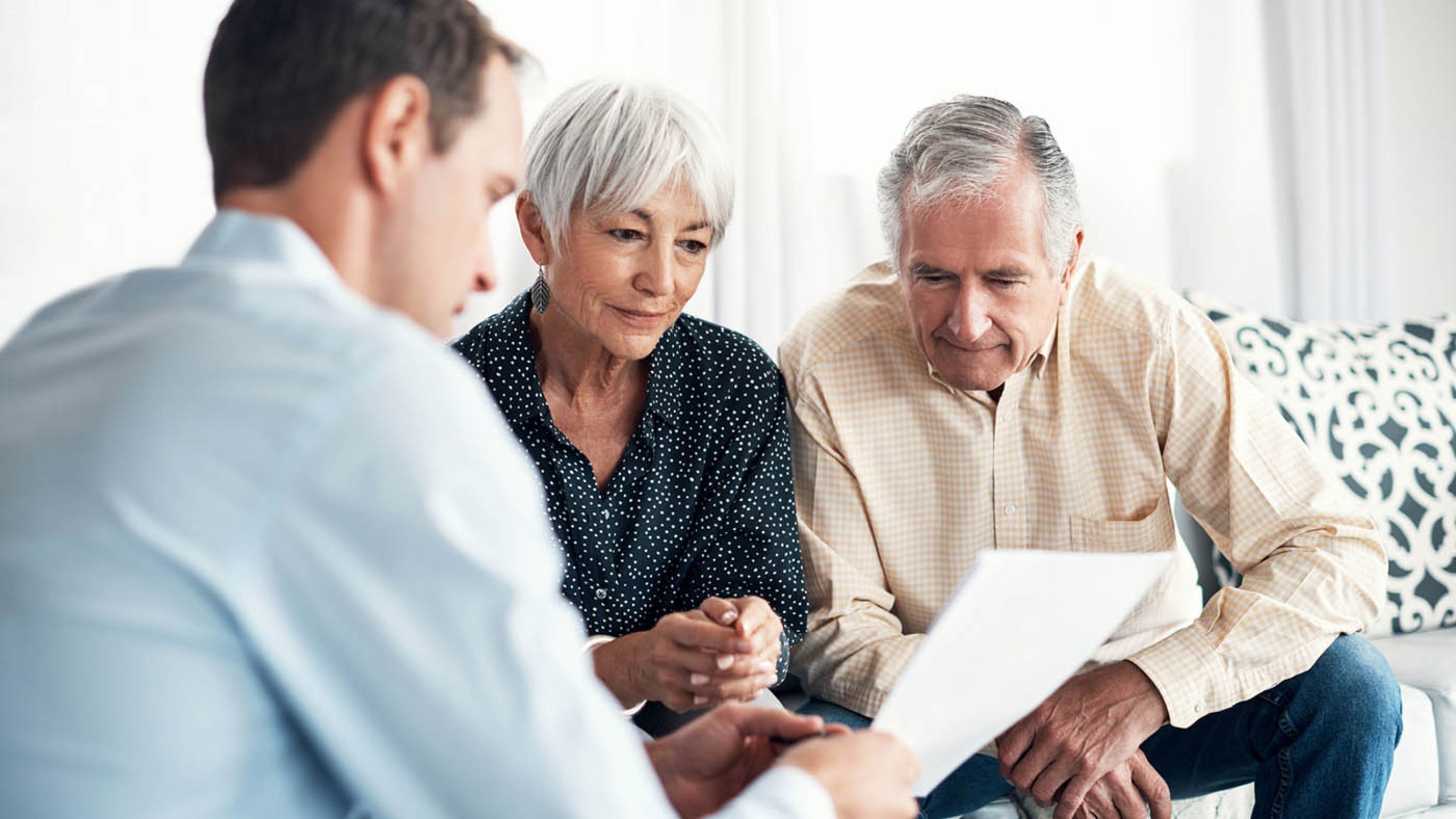 Eine Fachperson berät zwei Senioren bezüglich Testament und Erbschaft